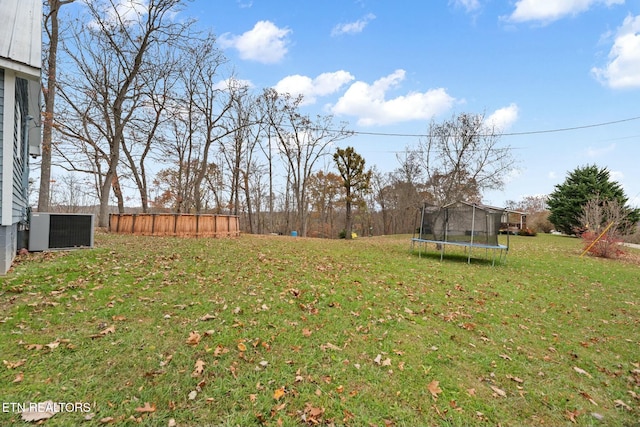 view of yard with a trampoline and central air condition unit