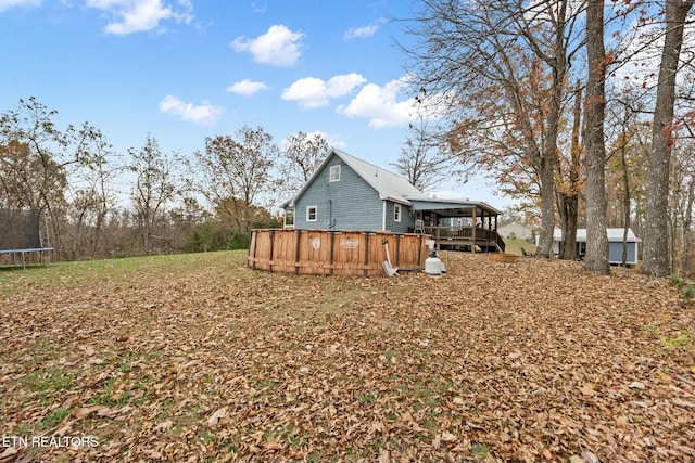 view of yard featuring a jacuzzi, a deck, and a trampoline