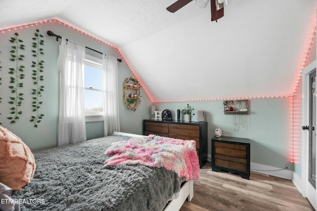 bedroom with ceiling fan, wood-type flooring, a textured ceiling, and lofted ceiling