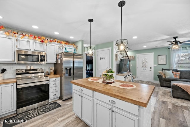 kitchen featuring hanging light fixtures, white cabinets, wooden counters, and appliances with stainless steel finishes