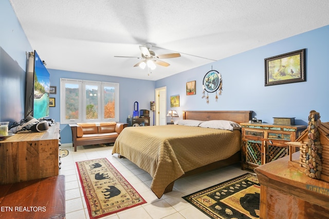 bedroom with ceiling fan, light tile patterned floors, and a textured ceiling