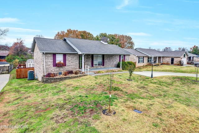 ranch-style house with a front lawn, a storage unit, and central AC