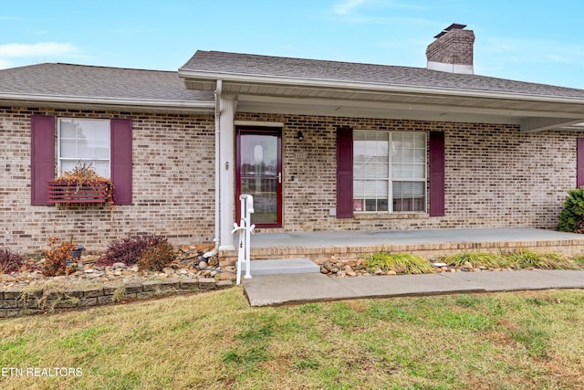 doorway to property with a porch and a yard