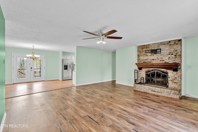 unfurnished living room with a fireplace, hardwood / wood-style floors, ceiling fan with notable chandelier, and a textured ceiling