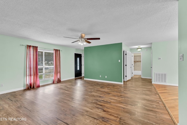 empty room featuring hardwood / wood-style floors, ceiling fan, and a textured ceiling