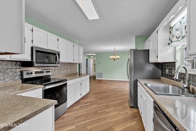 kitchen featuring white cabinets, decorative light fixtures, and stainless steel appliances