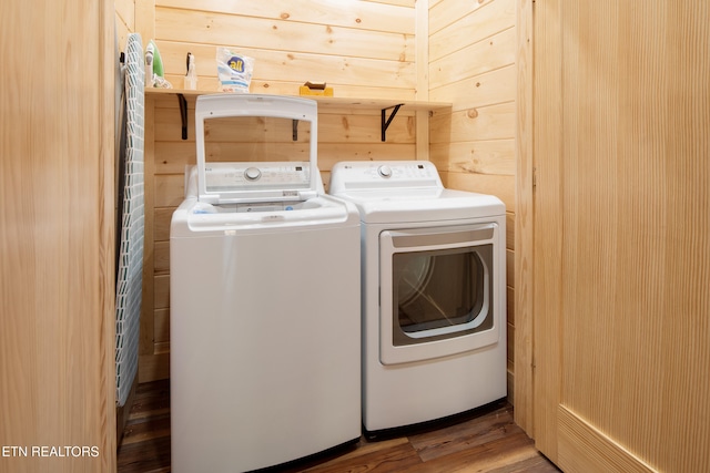 laundry area with hardwood / wood-style floors, washer and clothes dryer, and wood walls