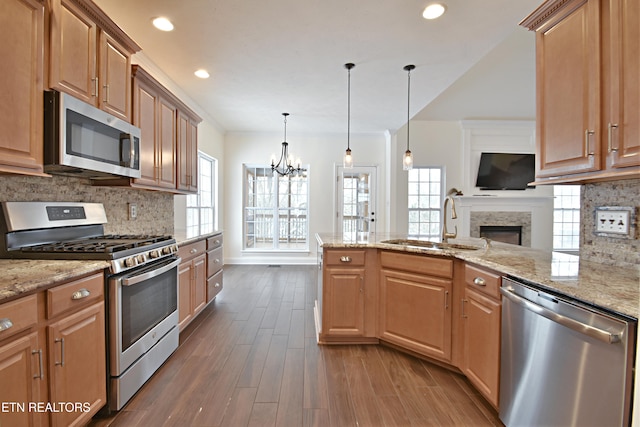 kitchen featuring dark wood-type flooring, an inviting chandelier, a fireplace, decorative light fixtures, and stainless steel appliances