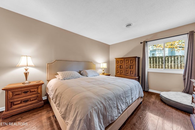 bedroom with a textured ceiling and dark hardwood / wood-style floors