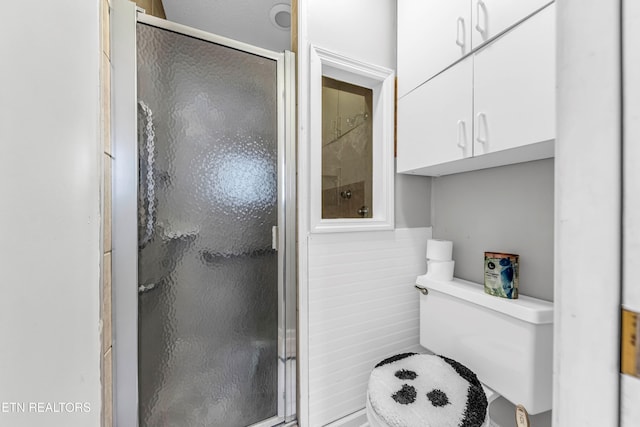 bathroom featuring wood walls, toilet, and walk in shower