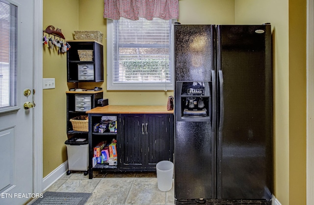 kitchen with wood counters and black refrigerator with ice dispenser