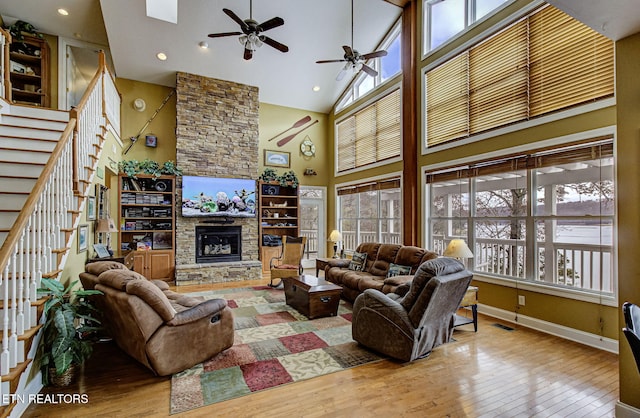 living room featuring ceiling fan, a fireplace, high vaulted ceiling, and light hardwood / wood-style flooring