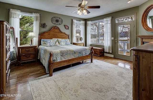 bedroom featuring multiple windows, access to exterior, ceiling fan, and hardwood / wood-style flooring