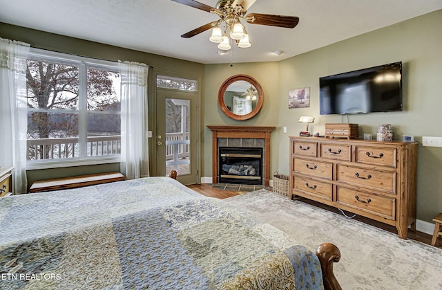 bedroom featuring ceiling fan, a tile fireplace, and light hardwood / wood-style flooring