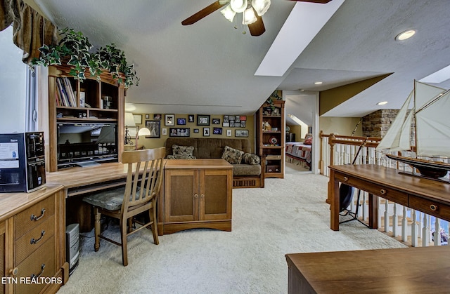 carpeted office space featuring ceiling fan, a textured ceiling, and a skylight