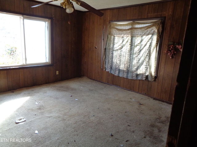 carpeted empty room featuring ceiling fan and wood walls