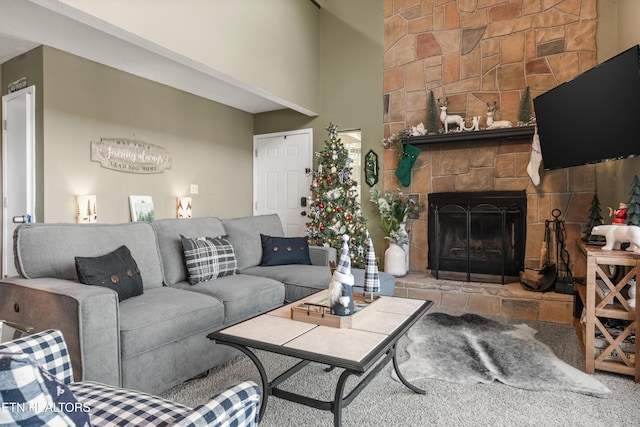 living room with carpet flooring, a towering ceiling, and a stone fireplace