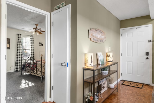 foyer with ceiling fan, parquet flooring, and a textured ceiling