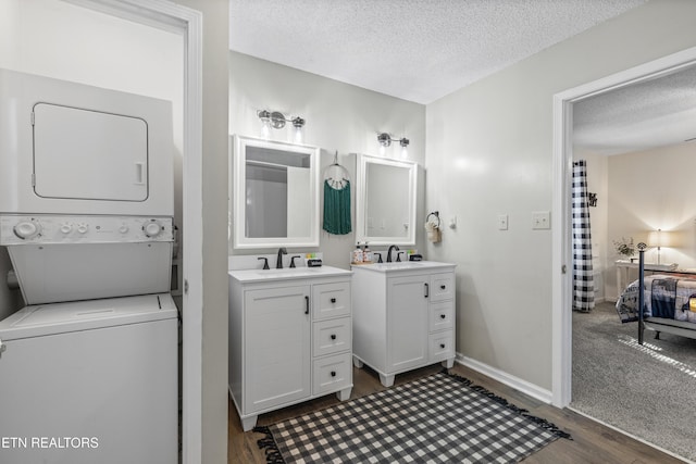 bathroom featuring hardwood / wood-style flooring, vanity, stacked washer and dryer, and a textured ceiling