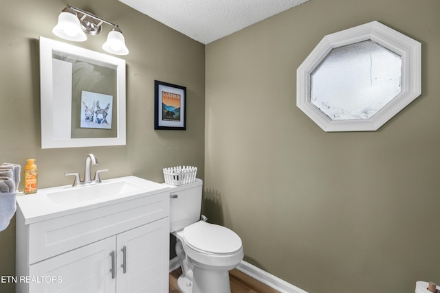 bathroom featuring vanity, hardwood / wood-style floors, a textured ceiling, and toilet