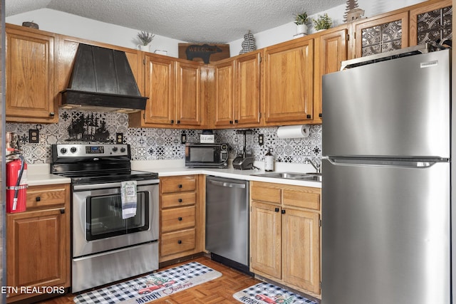 kitchen with a textured ceiling, custom range hood, parquet flooring, and appliances with stainless steel finishes