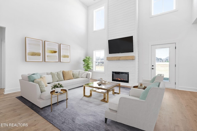 living room with a large fireplace, wood-type flooring, and a high ceiling