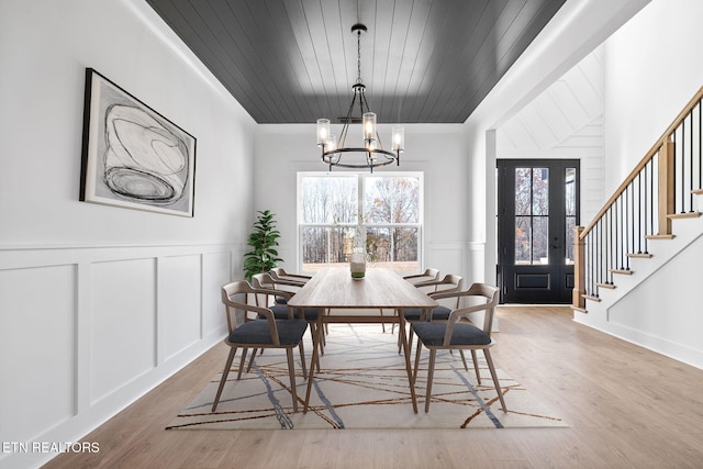 dining room featuring light hardwood / wood-style floors, wooden ceiling, and a chandelier