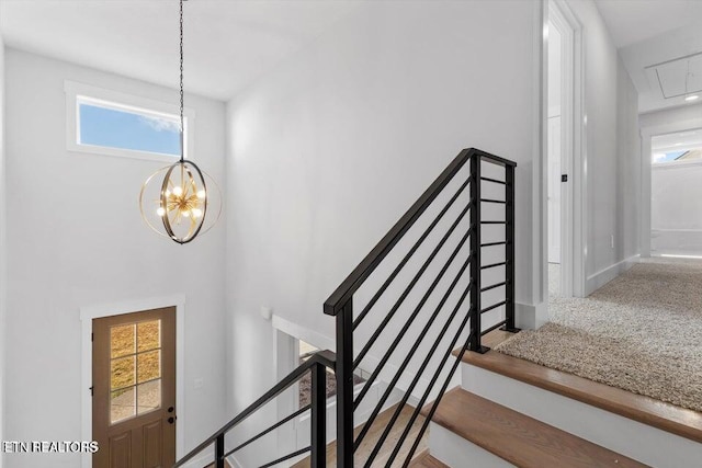 staircase with carpet floors, a healthy amount of sunlight, and an inviting chandelier