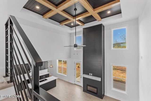 interior space with ceiling fan, beamed ceiling, a healthy amount of sunlight, and coffered ceiling