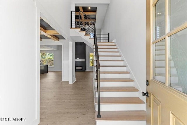 stairway with hardwood / wood-style floors and beam ceiling