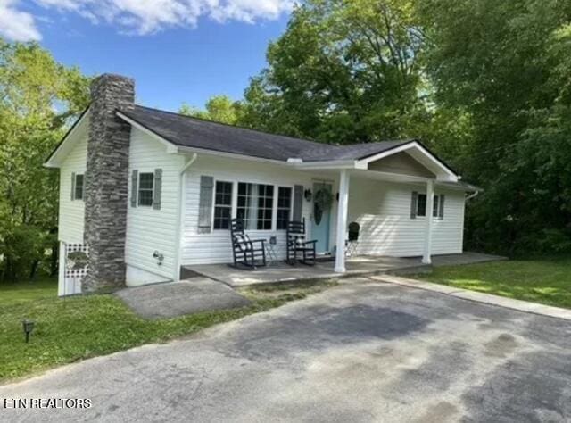 back of property featuring a lawn and a porch