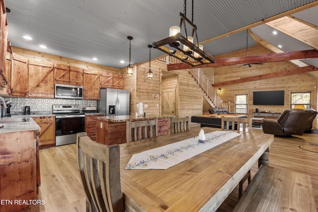 dining space with sink, light hardwood / wood-style flooring, billiards, wood walls, and lofted ceiling