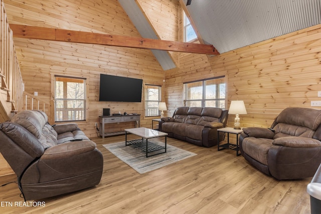 living room with wood walls, a healthy amount of sunlight, beamed ceiling, and high vaulted ceiling