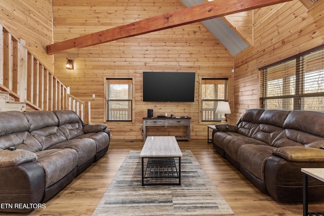 living room with plenty of natural light, high vaulted ceiling, light hardwood / wood-style floors, and beamed ceiling