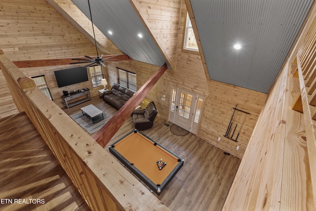 unfurnished living room with ceiling fan, dark wood-type flooring, wooden walls, high vaulted ceiling, and billiards