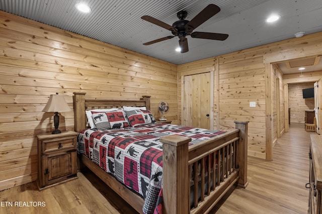 bedroom featuring wood walls, ceiling fan, and light wood-type flooring