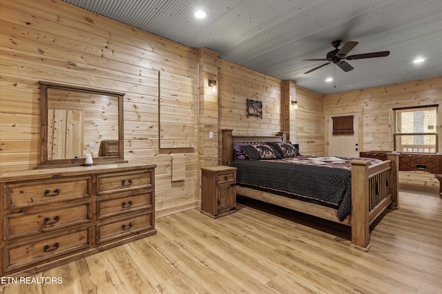 bedroom with light hardwood / wood-style flooring, ceiling fan, and wood walls