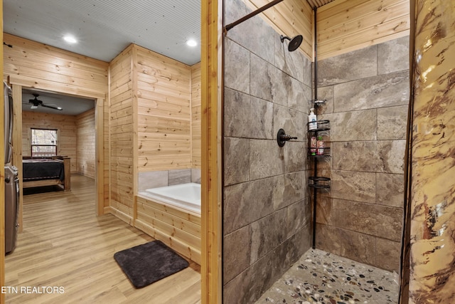 bathroom with ceiling fan, wooden walls, plus walk in shower, and hardwood / wood-style flooring