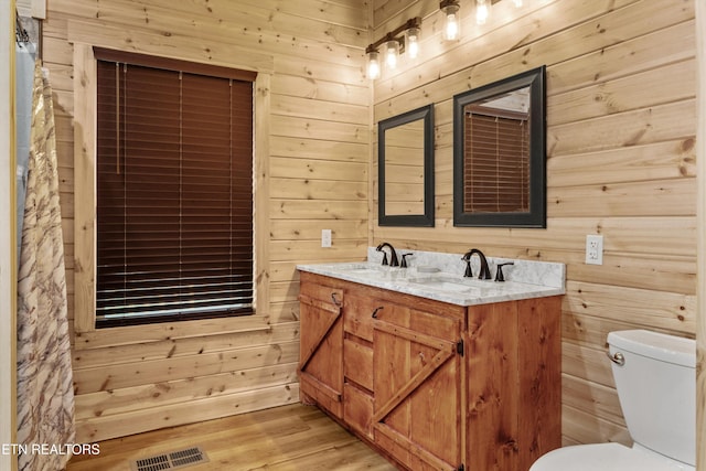 bathroom with wood walls, toilet, vanity, and hardwood / wood-style flooring