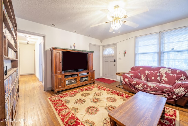 living room featuring wood-type flooring, a textured ceiling, and ceiling fan