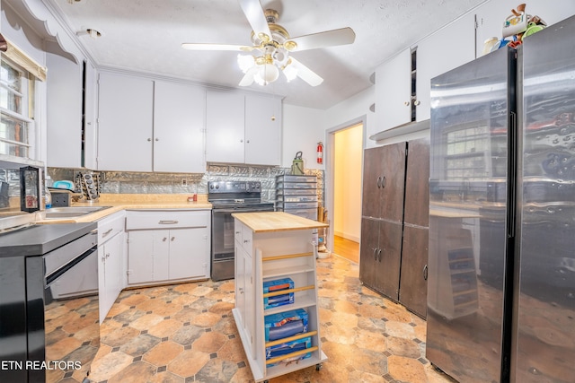 kitchen featuring black electric range oven, backsplash, sink, white cabinetry, and stainless steel refrigerator