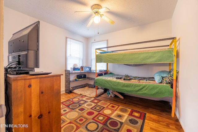 bedroom featuring ceiling fan, hardwood / wood-style floors, and a textured ceiling