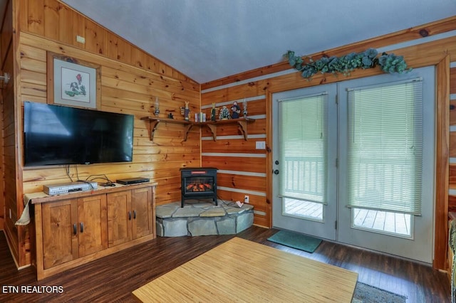 living room with a wood stove, wooden walls, vaulted ceiling, and dark wood-type flooring