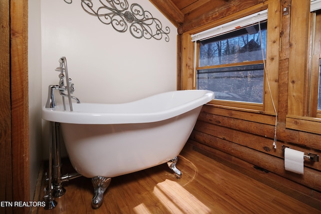 bathroom with hardwood / wood-style flooring and a tub to relax in