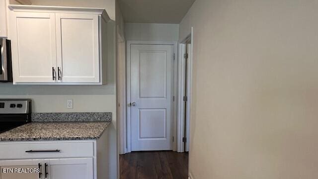 kitchen featuring dark stone countertops, dark hardwood / wood-style flooring, white cabinets, and appliances with stainless steel finishes