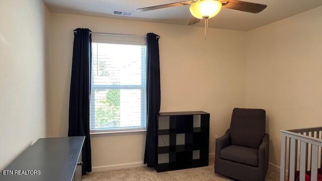 bedroom with a crib, light carpet, and ceiling fan