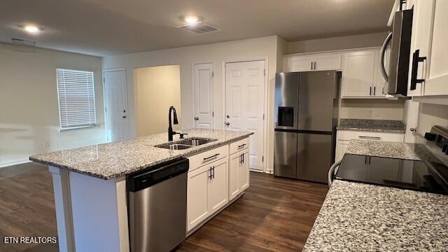 kitchen with white cabinets, sink, dark hardwood / wood-style floors, an island with sink, and stainless steel appliances