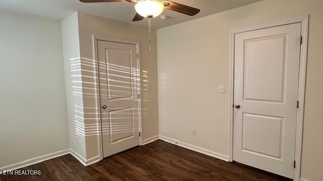 unfurnished bedroom with ceiling fan and dark wood-type flooring