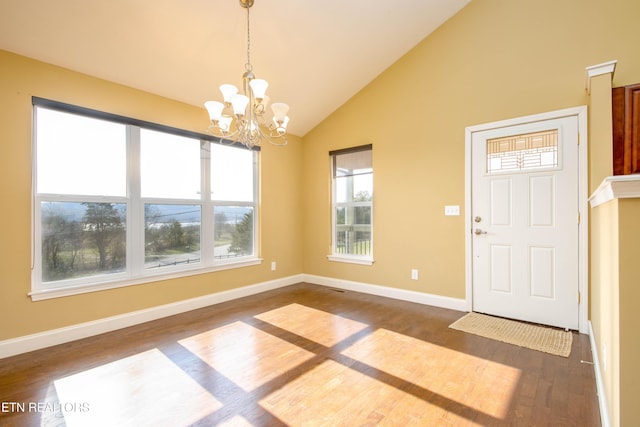 foyer entrance featuring a notable chandelier, dark wood-type flooring, and high vaulted ceiling