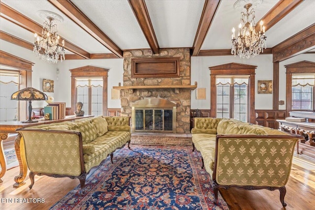 living room with beam ceiling, a stone fireplace, and wood-type flooring